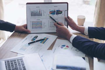 financial Image of two young business people pointing at business document during discussion at meeting , Notebook on wood table