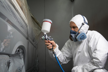 Painter spray gun in the hands of a painter.