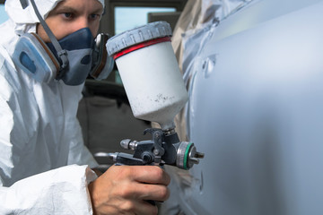 Painter spray gun in the hands of a painter.