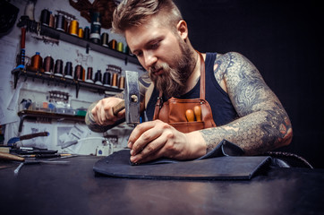 Close up of a shoemaker man working with leather using crafting tools