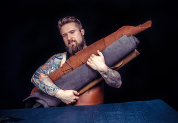 Leather craft or leather working. Selected pieces of beautifully colored or tanned leather in leather craftman's tattooed hands