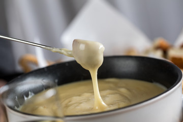 Mann dippt Brot in Schweizer Käsefondue