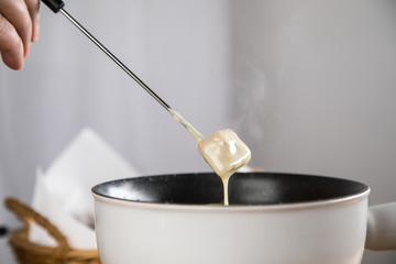 Mann isst Brot bei Käsefondue mit Fonduegabel 