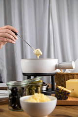 Mann isst Brot mit Schweizer Käsefondue, Oliven und Cornichons