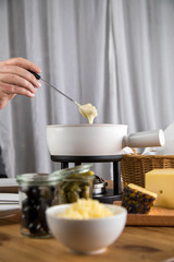 Mann isst klassisches Käse Fondue mit Brot und Käseplatte