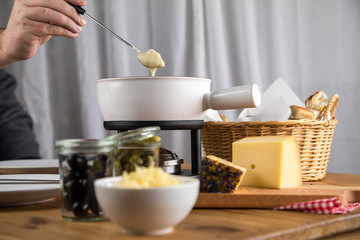 Mann isst Brot mit Schweizer Käsefondue, Oliven und Cornichons