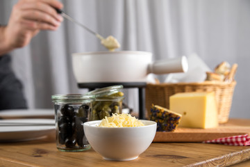 Mann isst Brot mit Schweizer Käsefondue, Oliven und Cornichons
