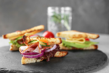 Slate plate with delicious sandwich on table, closeup