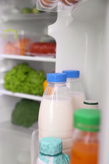 Obraz na płótnie Canvas Bottles with milk on refrigerator shelf, closeup