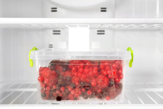 Container with berries in refrigerator