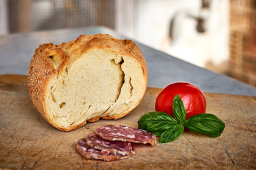 Pane siciliano, salame affettato, pomodoro e basilico su tagliere