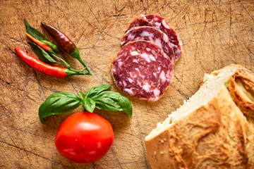 Pane siciliano, salame affettato, pomodoro e basilico su tagliere