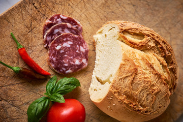 Pane siciliano, salame affettato, pomodoro e basilico su tagliere
