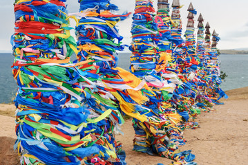 Wooden ritual pillars with colorful ribbons Hadak on cape Burkhan. Lake Baikal. Olkhon Island....