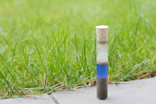 Checking the ph value of garden soil with a simple ph metre. Soil and reagent liquid in a glass test tube. glass tube with plug on it. Blue color showing neutral ph value.