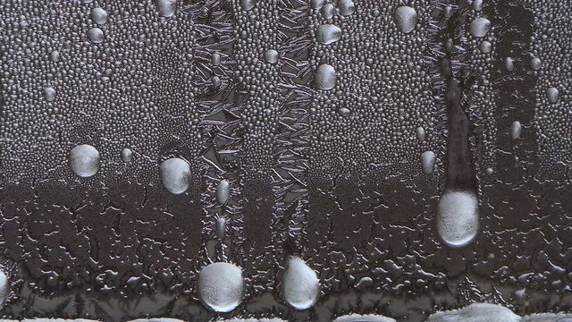 Closeup macro of ice crystals on window melting, time lapse, then reversing direction.