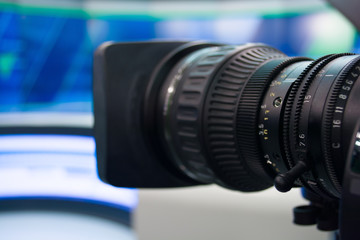 Fototapeta na wymiar detail of video camera, film lens in blur tv studio background