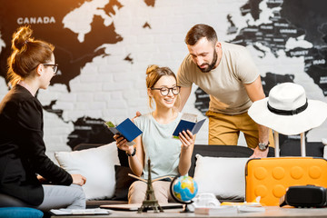 Young lovely couple sitting with manager at the travel agency office prepairing for a summer...
