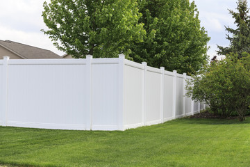Fototapeta na wymiar Contemporary white vinyl fence surrounding yard