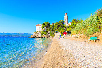 Pebble stone beach and view of Dominican monastery in distance, Bol town, Brac island, Croatia