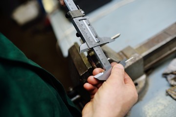 close-up a worker holds a caliper in her hands and measures a detail