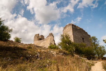 ruins on top of hill with blue sky and white clouds in background