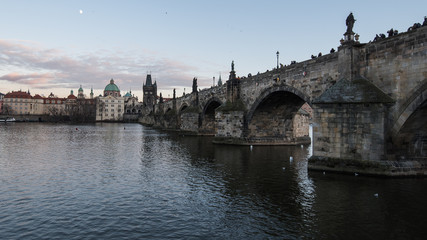 Obraz premium View of 14th century Charles bridge and old Town Prague across the Vltava (Moldau) river. Picture taken from left bank on late afternoon in winter.