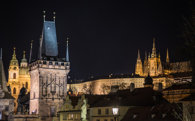 Fototapeta premium A night view of Prague taken from the Charles bridge depicting multiple towers and spires - the historic skyline and Prague castle on the hill. The historic landmarks are illuminated.