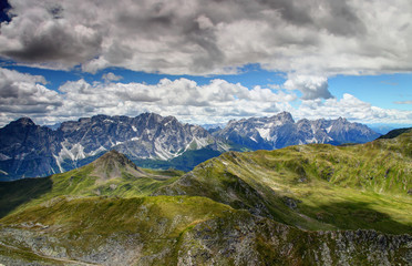 Gentle green slopes of Carnic Alps and  jagged rock faces Sexten Dolomites with Monte Popera, Cima Undici, Croda Rossa di Sesto and Punta dei Tre Scarperi peaks, Belluno and South Tyrol, Italy, Europe
