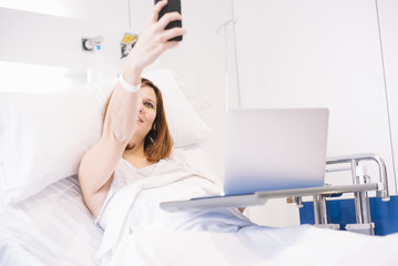 Obraz na płótnie Canvas ill woman with Smartphone and laptop in the hospital