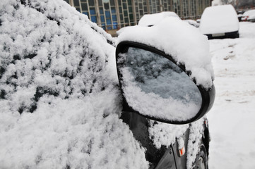 Car side mirror covered in snow on the parking lot
