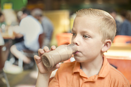 Boy drinking chocolate milk during lunch at his school cafeteria