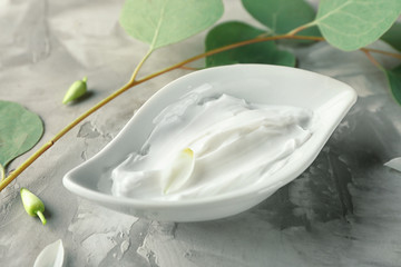 Bowl with body cream on grey textured background
