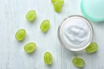 Jar with body cream and grapes on white wooden background