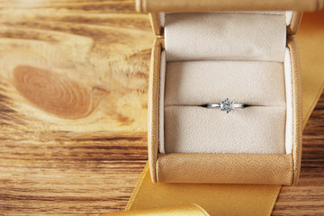 Box with luxury engagement ring on wooden background