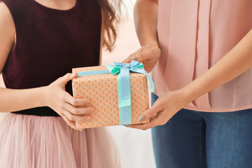 Little girl giving gift box to her mom indoors. Mother's day celebration