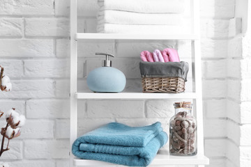 Clean towels with soap dispenser on shelves in bathroom