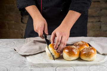 Close up view of baker cooking bread buns for burger. Hands preparing bread dough on wooden table. Preparing traditional homemade bread. Hotel service concept.