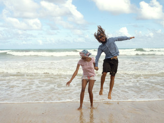 A girl and a man are jumping near the sea