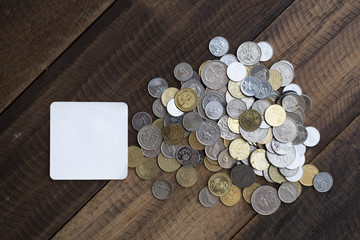 saving concept - coins in a jar with white empty note on a wooden table / background