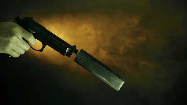 sinister foggy scene with handgun with suppressor being brought up and fired