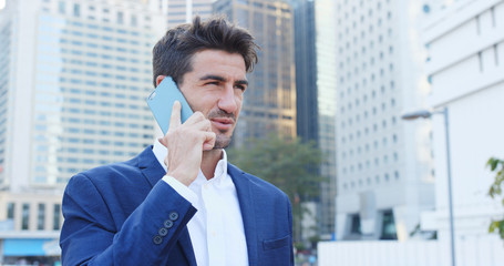 Businessman talk to cellphone over cityscape background, serious talking, replying customer