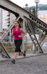 woman jogging across the bridge at sunny morning