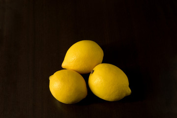 Group of three lemons - view from above on dark background - dark food photography, copy space