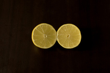 Single lemon sliced in half - on dark background - dark food photography, copy space