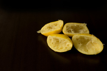 Squeezed lemon skins on dark background - lemon peel - dark food photography, copy space