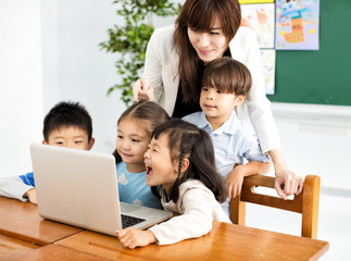  children looking at the laptop with teacher near by