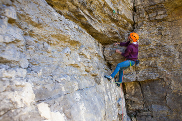 The woman in the helmet climbs the rock.