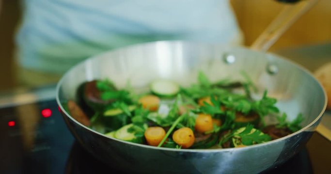 Close up of woman sautéing vegetables in pan