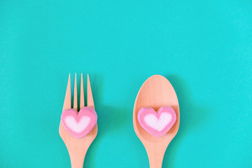 Heart shape of pink marshmallow on spoon and fork wood on green background with copy space. Concept...